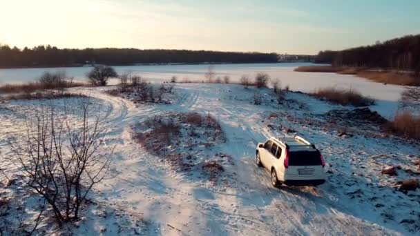 Vista aérea de un coche todoterreno que se detiene en la playa del lago con agua congelada — Vídeo de stock