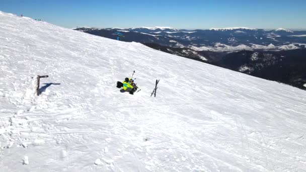 Пара лыжников и сноубордистов веселятся на вершине холма в солнечный день — стоковое видео