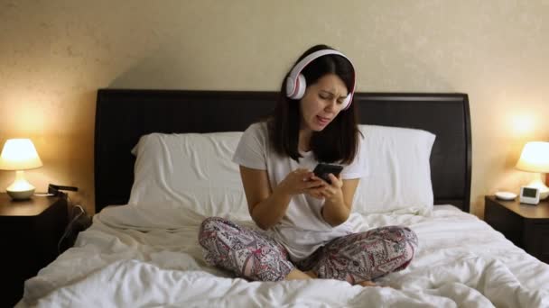 Wanita mendengarkan di tempat tidur mendengarkan musik dengan headset — Stok Video