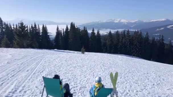 Лыжник и сноубордист, отдыхающий на вершине холма — стоковое видео