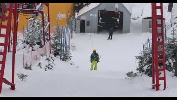 Dragobrat, Ukraina - 11 stycznia 2021: człowiek narciarz podjeżdża jarzmem na szczyt zaśnieżonego wzgórza — Wideo stockowe