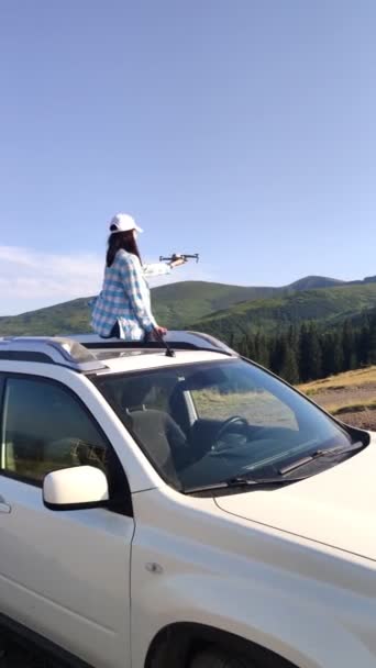 Γυναίκα κάθεται σε SUV αυτοκίνητο εκκίνησης drone από το χέρι για να πυροβολήσει βουνά γύρω — Αρχείο Βίντεο