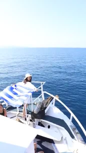 那女人拿着希腊国旗扬帆在小船上弯腰绕过左卡达岛 — 图库视频影像