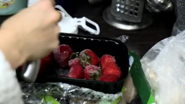 Женщина убирает замороженную клубнику на кухне — стоковое видео