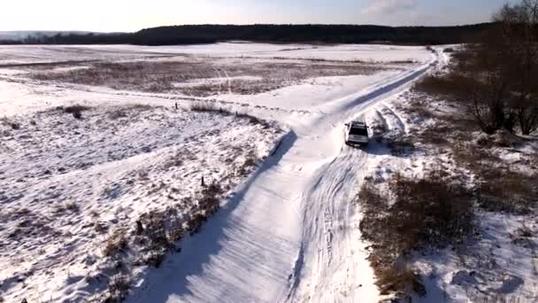 Widok z lotu ptaka SUV-a poruszającego się po zaśnieżonym polu — Wideo stockowe