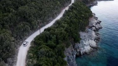 Arazi aracının havadan görünüşü deniz manzaralı dağ yolundan gidiyor.