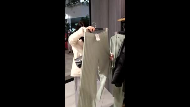 Frau wählt Kleidung im Einkaufszentrum — Stockvideo