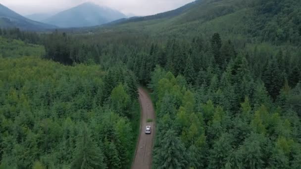 Luftaufnahme eines Geländewagens, der sich auf einer Straße im Gebirge bewegt, bewölkt und regnerisch — Stockvideo