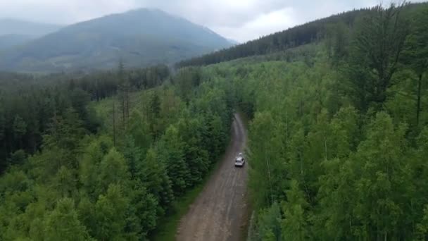 Vista aérea do carro SUV movendo-se pela estrada caminho em montanhas nublado tempo chuvoso nebuloso — Vídeo de Stock