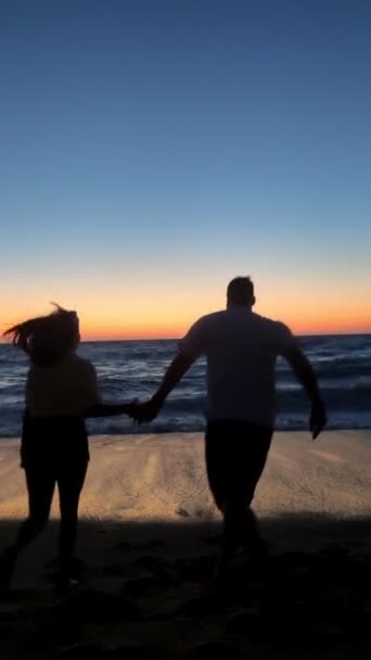 Couple profitant du coucher de soleil au-dessus de la mer orageuse avec de grandes vagues — Video