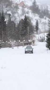 4x4 araç karlı tepenin yanından geçiyor.