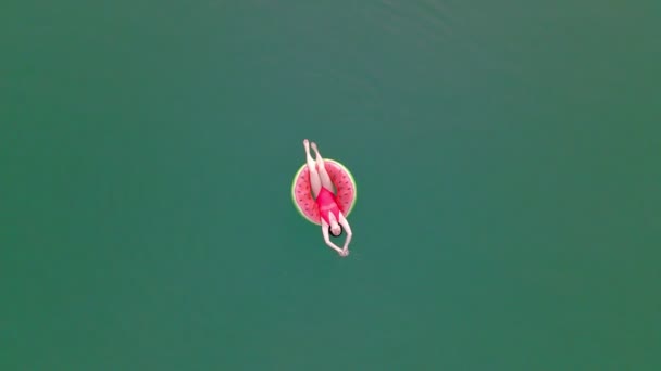 Górny widok z góry kobieta pływanie z arbuzem pływanie koło w niebieskiej wodzie — Wideo stockowe