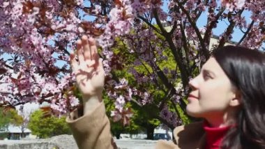 Kadın pembe sakura ağacı kokusu alıyor.