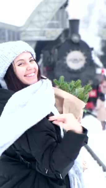 Fenyőfa csokor női kézben vár a vasútállomáson — Stock videók