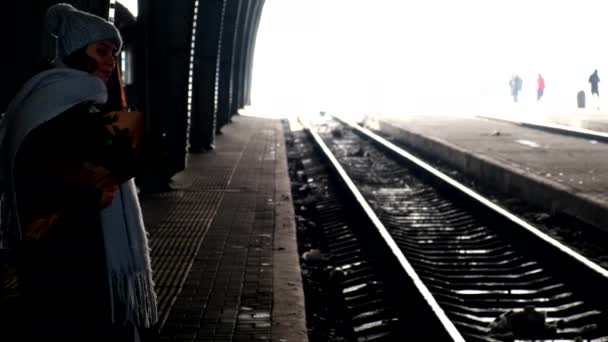 Kvinna väntar på tåg på järnvägsplattform med tall bukett — Stockvideo