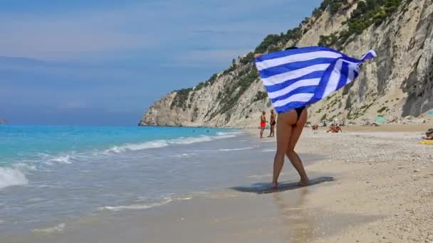 Mulher correndo com bandeira grega pela praia de egremni — Vídeo de Stock