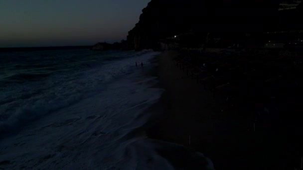 Paar betrachtet Sonnenuntergang über dem Meer mit großen Wellen — Stockvideo