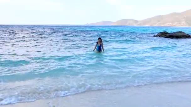 Vrouw in blauw badpak uitstappen uit de zee — Stockvideo