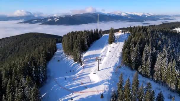 Vista aérea de la estación de esquí en las montañas cubiertas de pinos — Vídeos de Stock