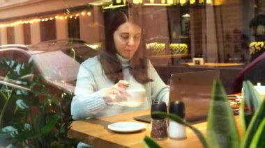 Kafede dizüstü bilgisayarda çalışan serbest çalışan bir kadın.