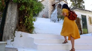 Sarı elbiseli güzel bir kadın, Yunan caddesinde yürüyor.