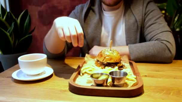 Człowiek w kawiarni je hamburgery i frytki — Wideo stockowe