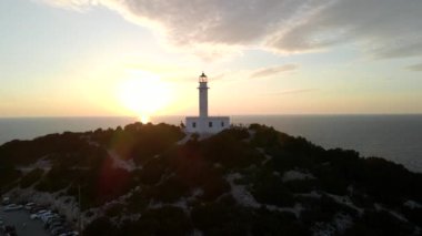Soldaki deniz fenerinin günbatımındaki hava manzarası.
