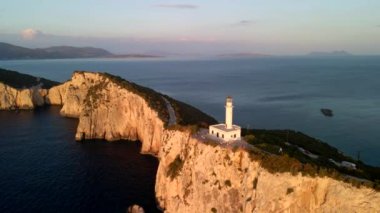 Soldaki deniz fenerinin günbatımındaki hava manzarası.