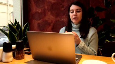 Kafede bilgisayarda görüntülü konuşma yapan kadın uzaktan çalışıyor.