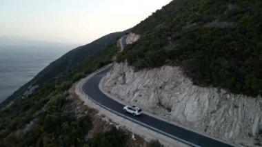 Araba yolculuğu konsepti. Soldaki adada deniz kenarındaki dağ yolunun havadan görünüşü.