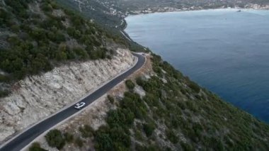 Araba yolculuğu konsepti. Soldaki adada deniz kenarındaki dağ yolunun havadan görünüşü.