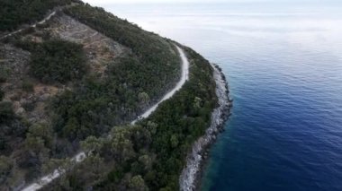 Arazi aracının havadan görünüşü deniz manzaralı dağ yolundan gidiyor.