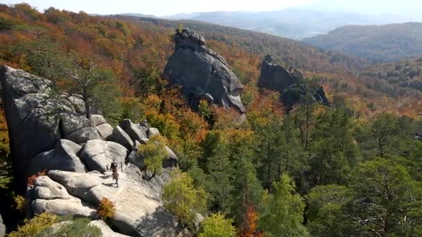 Visão da órbita aérea de caminhantes casal no topo da rocha no meio da floresta de outono — Vídeo de Stock