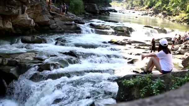 Vrouw wandelaar zittend op de rots kijkend naar waterval — Stockvideo