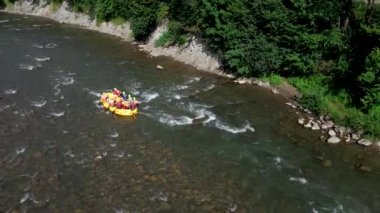 İnsanlar yaz güneşli bir günde dağda rafting yapıyor.