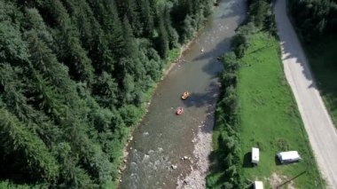 İnsanlar yaz güneşli bir günde dağda rafting yapıyor.