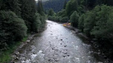 İnsanlar yaz güneşli bir günde dağda rafting yapıyor.