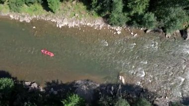 İnsanlar yaz güneşli bir günde dağda rafting yapıyor.