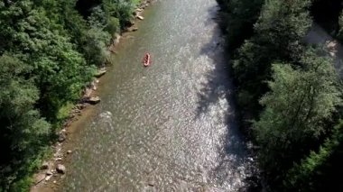 İnsanlar yaz güneşli bir günde dağda rafting yapıyor.