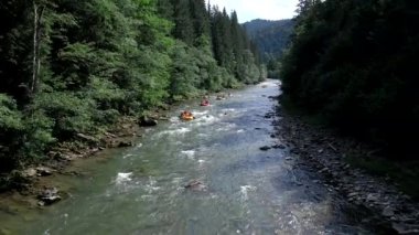 İnsanlar yaz güneşli bir günde dağda rafting yapıyor.