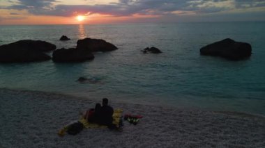 Çiftler gün batımında sahilde buluştu.