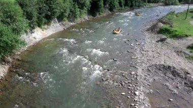 İnsanlar yaz güneşli bir günde dağda rafting yapıyor.