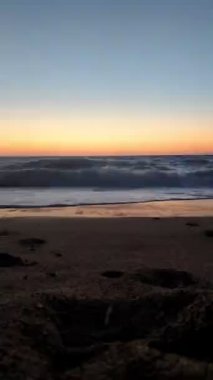 Genç bir kadın denize koşuyor, gün batımının tadını çıkarıyor.