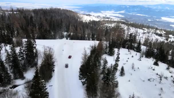 Widok z lotu ptaka samochód poruszający się drogą śnieżną w górach — Wideo stockowe