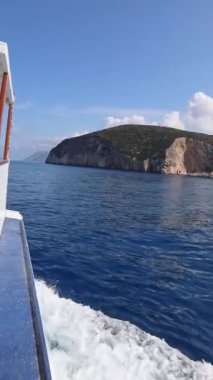 Mavi deniz kıyısından giden tekne adadan ayrılıyor.