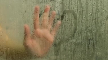Kadın duşa giriyor sisli camlara kalp çiziyor.