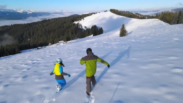 Felice coppia snowboarder sciatore salto nella neve rendendo angelo della neve — Video Stock