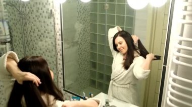 Banyoda aynanın önünde saçını tarayan bir kadın.