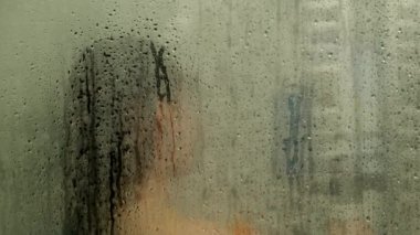 Kadın sisli camlardan duş alıyor.