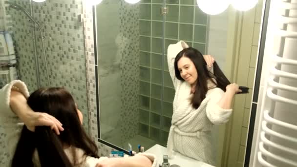 Woman brushing her hair in bathroom in front of mirror — Vídeos de Stock